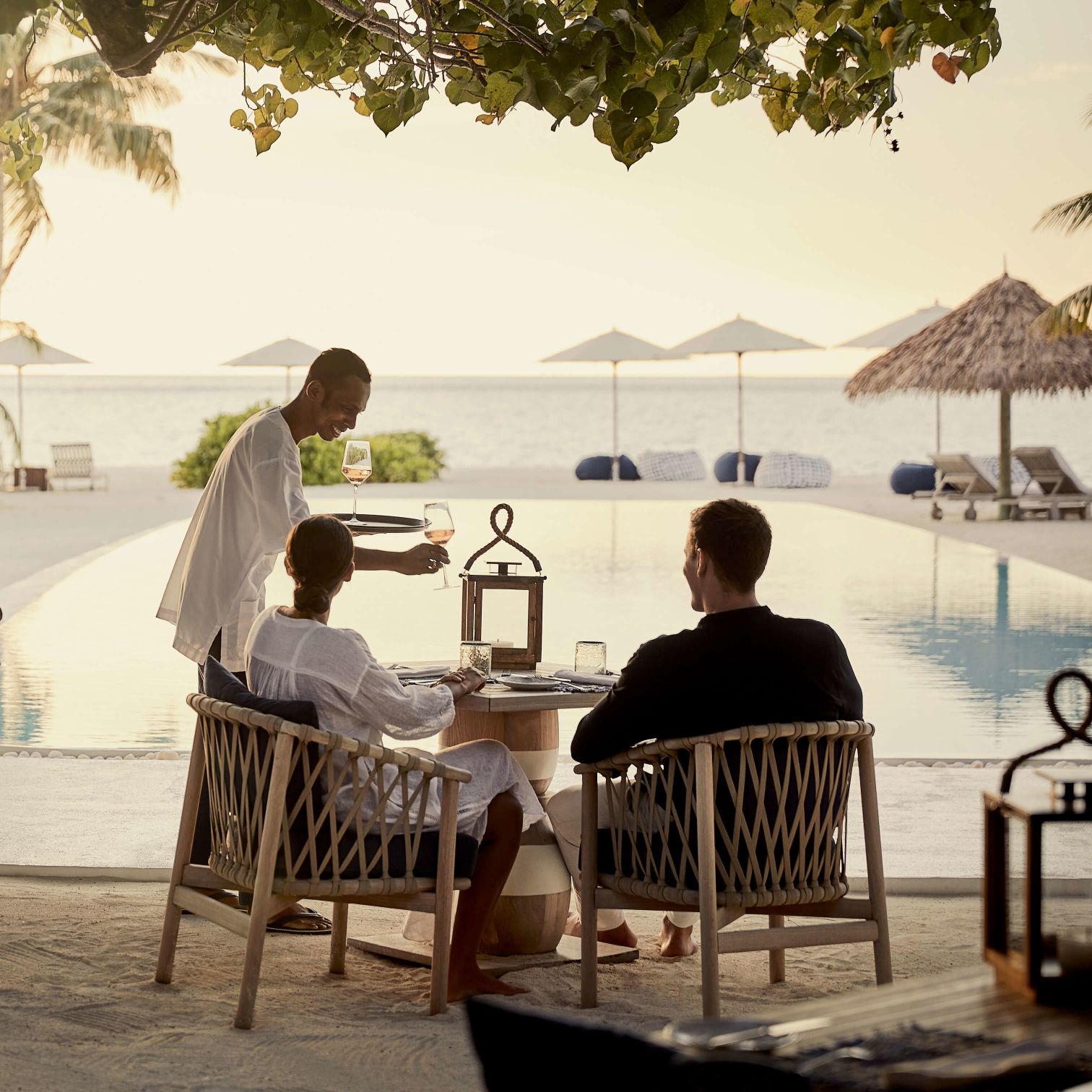 A Group Of People Sitting On A Bench Next To A Body Of Water